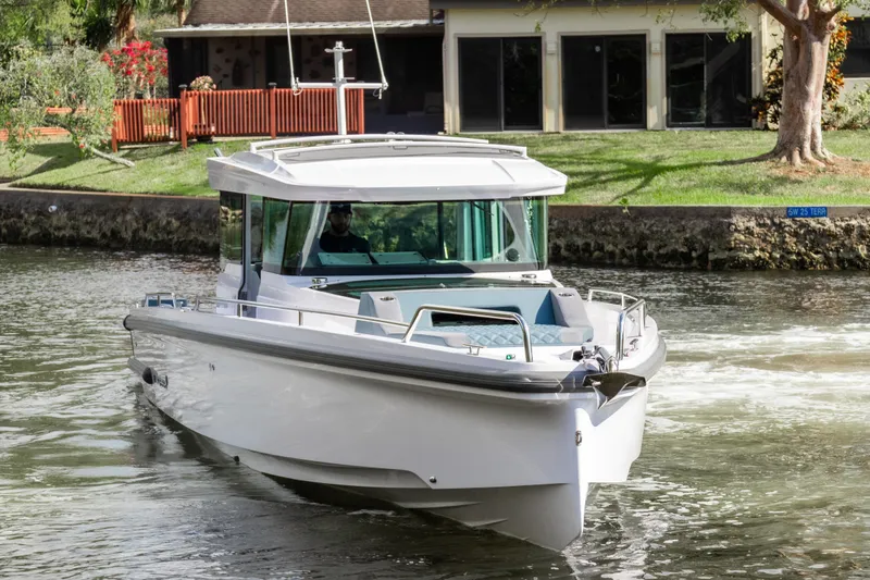Slide: The Image of 2024 Axopar 37XC CROSS CABIN cruising on a calm waterway near a residential area. - 6