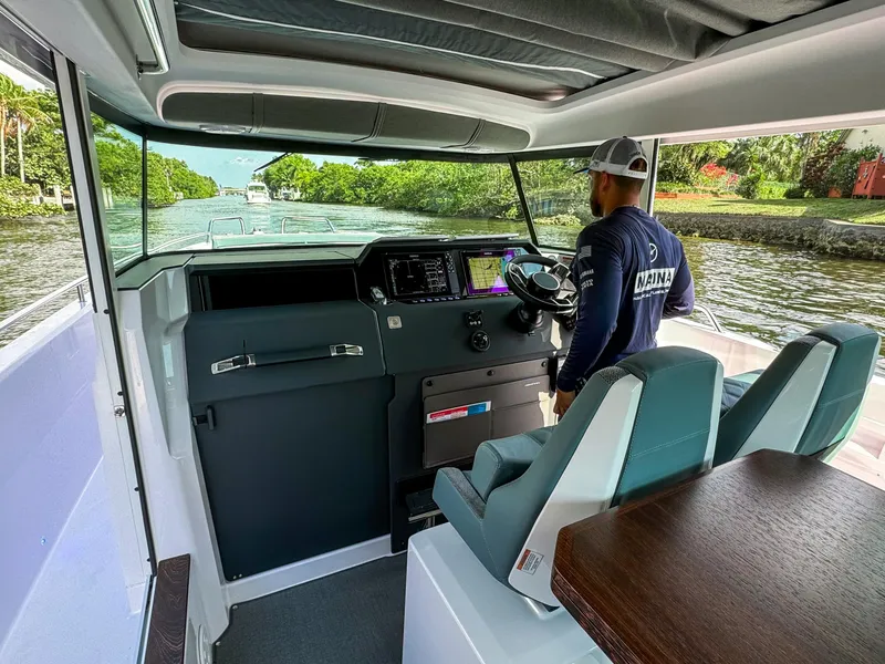 Slide: The Image of 2024 Axopar 37XC CROSS CABIN interior with captain navigating a scenic waterway. - 8
