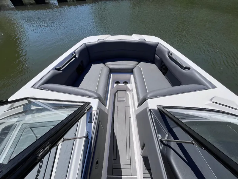 Slide: The Image of 2024 Moomba Max boat interior with gray seating, open bow design, and water view. - 12