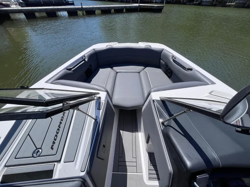 Slide: The Image of 2024 Moomba Max boat interior with gray seating, docked on calm water. - 13