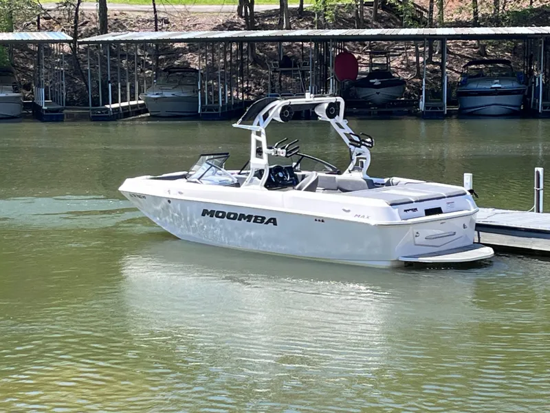 Slide: The Image of 2024 Moomba Max boat docked on a calm lake. - 2