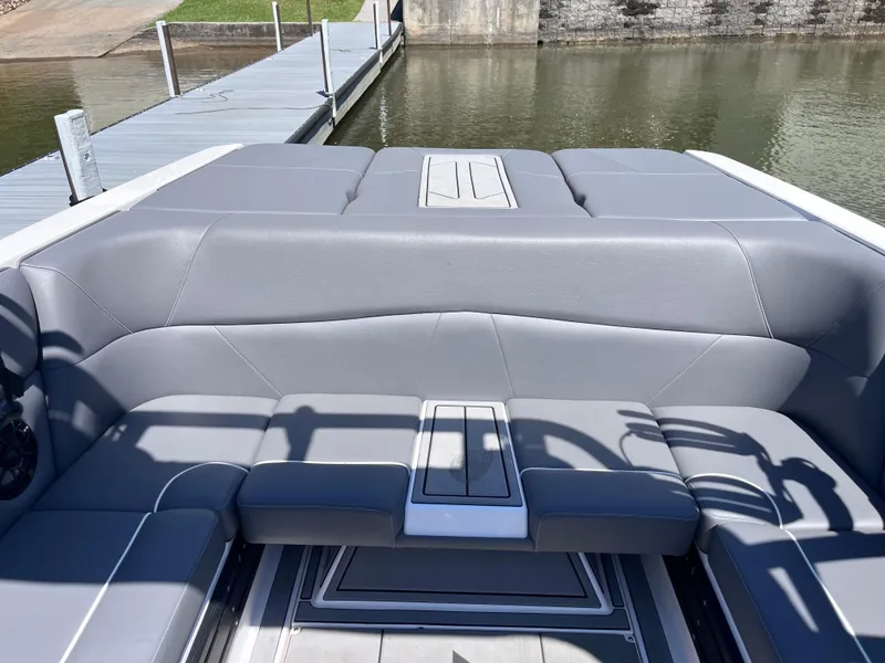 Slide: The Image of 2024 Moomba Max boat interior with gray seating near a dock. - 26