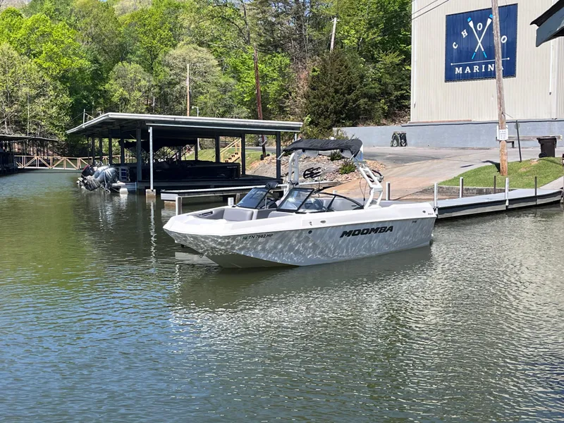 Slide: The Image of 2024 Moomba Max boat docked at a marina, surrounded by lush greenery. - 41
