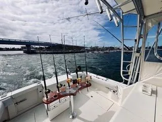 Slide: The Image of 2001 Carolina Classic 35 boat with fishing rods, cruising near a bridge under a cloudy sky. - 5