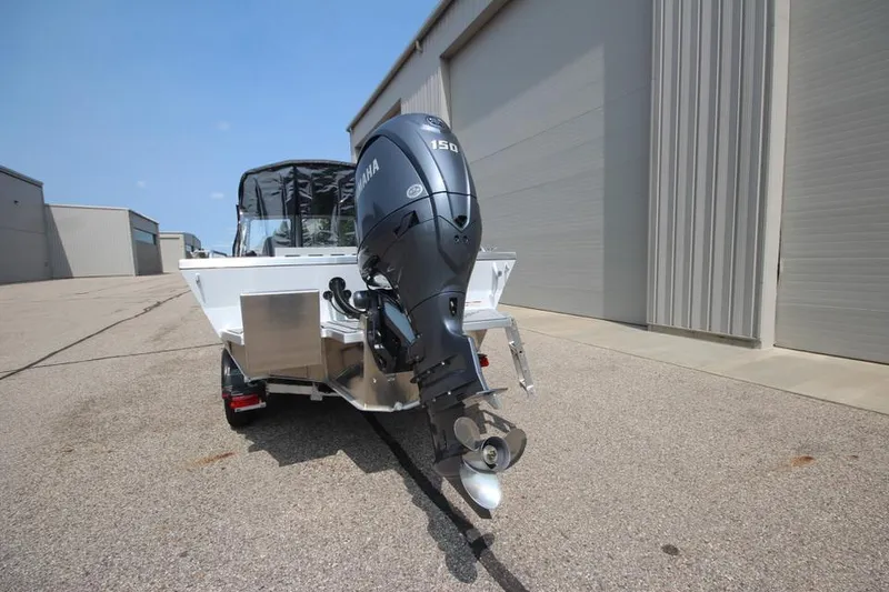 Slide: The Image of 2025 Weldcraft 200 Rebel F150 boat with Yamaha outboard motor, parked near warehouse. - 5
