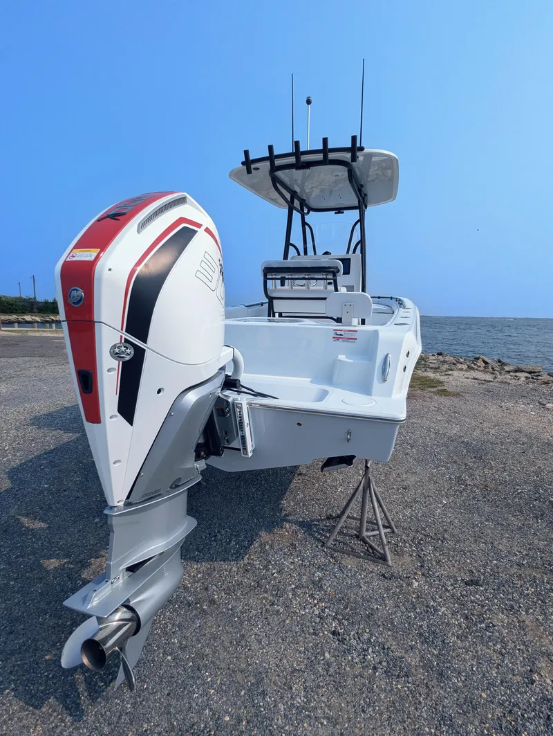 Slide: The Image of 2025 Contender 24 Sport boat with powerful outboard motor, parked near the shoreline. - 39