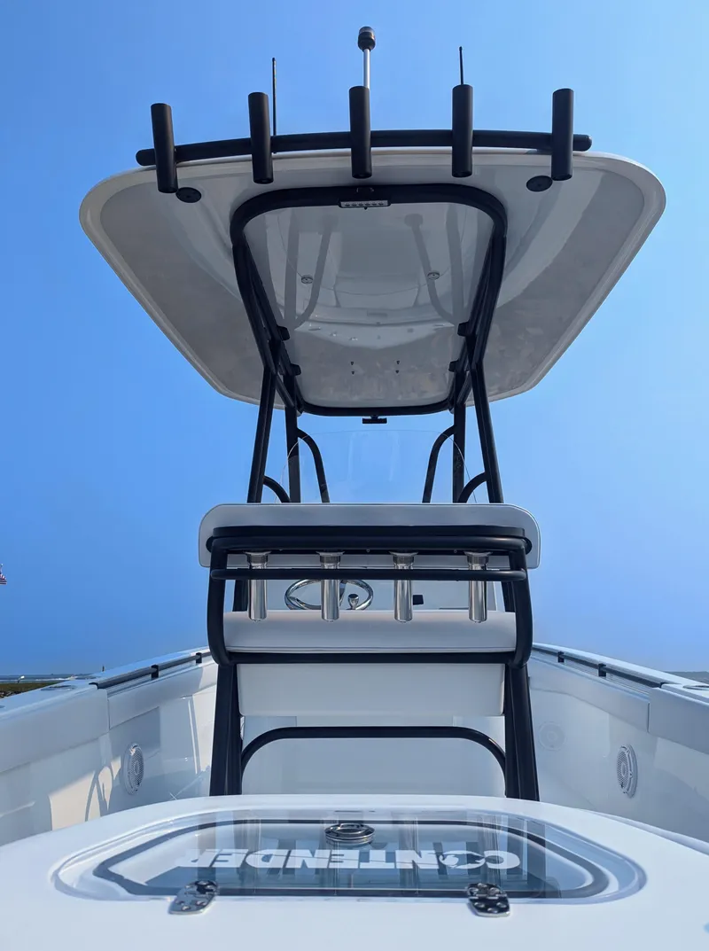 Slide: The Image of 2025 Contender 24 Sport boat with T-top and rod holders, viewed from the stern. - 49