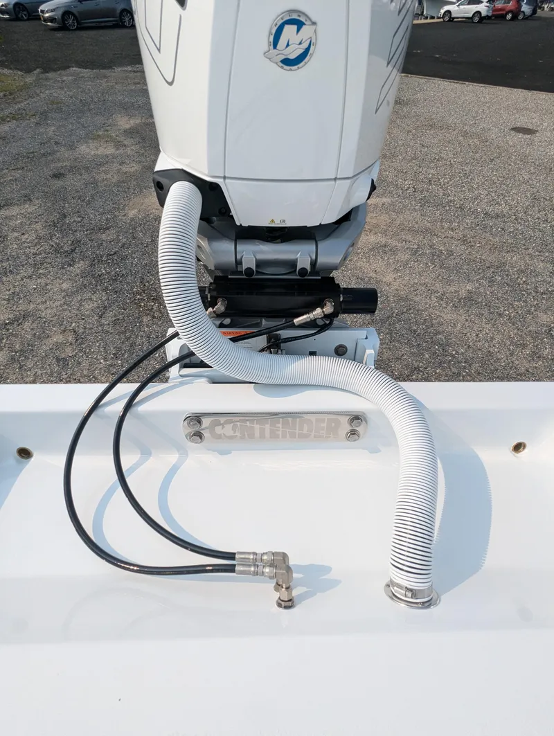 Slide: The Image of 2025 Contender 24 Sport boat engine with hoses on a gravel surface. - 7