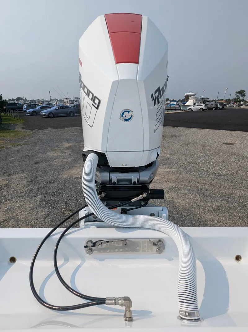 Slide: The Image of 2025 Contender 24 Sport boat engine with hoses, parked on gravel near marina. - 8