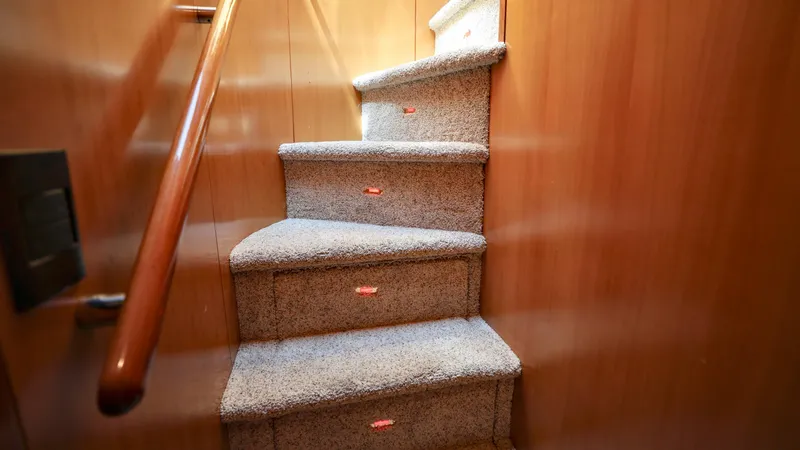 Slide: The Image of Carpeted stairs inside a 2004 Grand Harbour Motor Yacht with wooden handrail. - 10