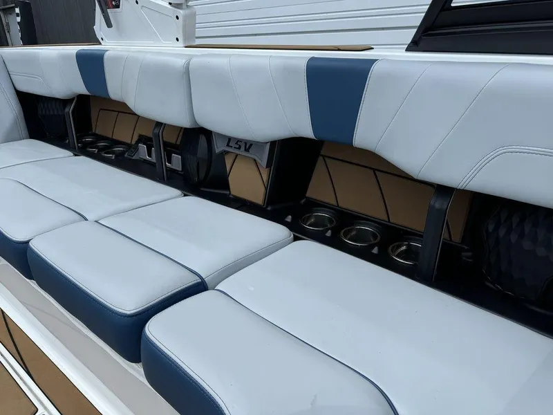 Slide: The Image of 2022 Malibu 23 LSV boat interior with white and blue seating and cup holders. - 12