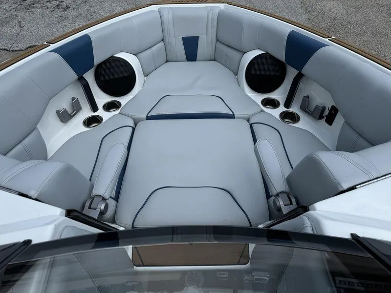 Slide: The Image of 2022 Malibu 23 LSV boat interior with gray and blue seating, cup holders, and speakers. - 13