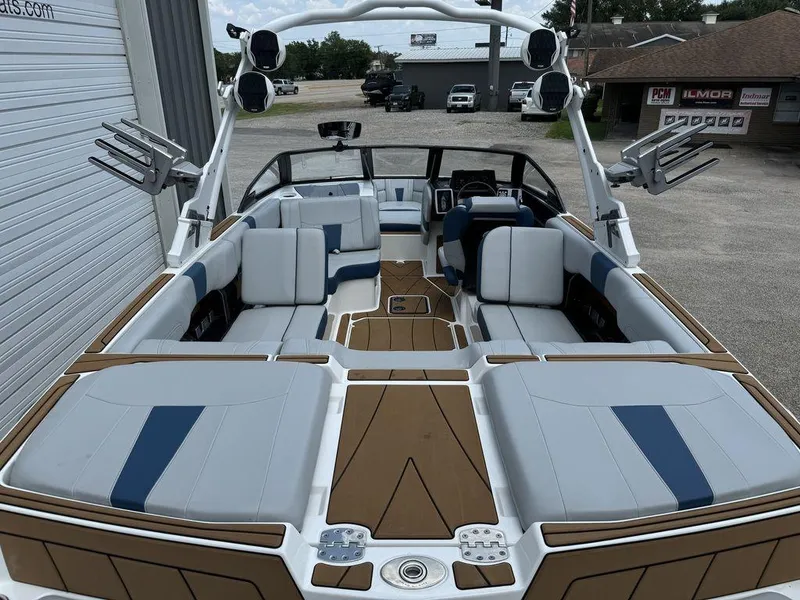 Slide: The Image of 2022 Malibu 23 LSV boat interior with white and blue seating, parked outdoors. - 5