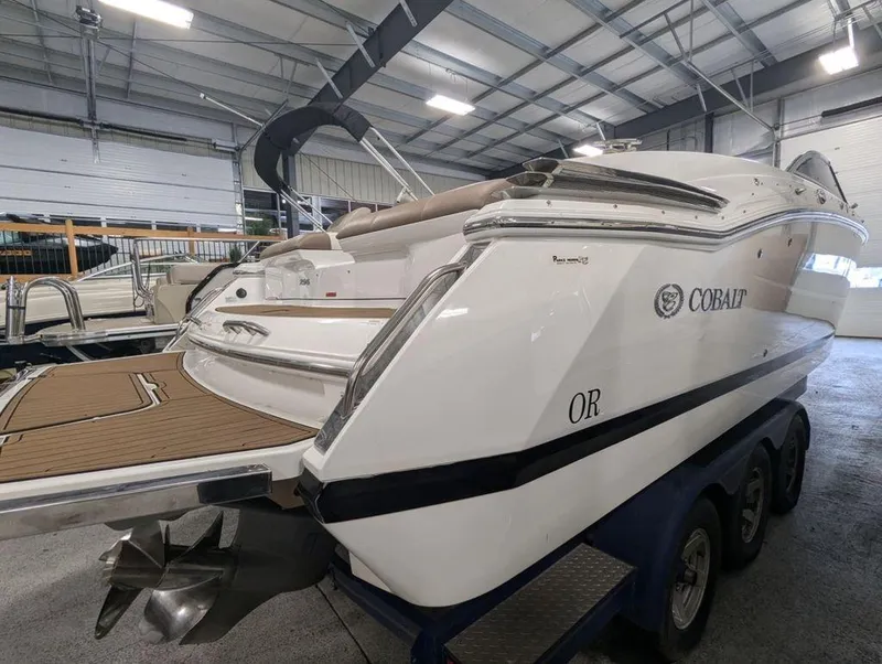Slide: The Image of 2014 Cobalt 296 boat in showroom, showcasing sleek design and triple-axle trailer. - 3