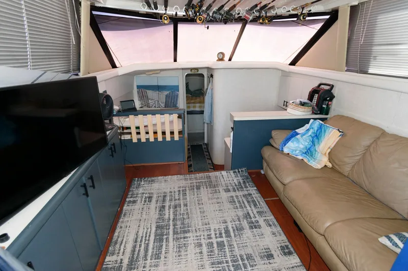 Slide: The Image of Interior of 1992 Silverton 34 Convertible boat with sofa, TV, and fishing rods. - 13