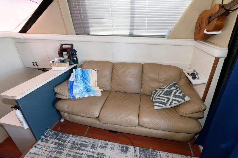 Slide: The Image of 1992 Silverton 34 Convertible interior with beige leather sofa, patterned pillow, and guitar on wall. - 14