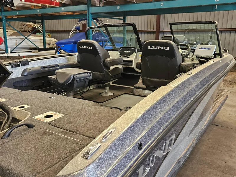 Slide: The Image of 2022 Lund TYEE boat interior with dual seats and Lowrance equipment in storage. - 4