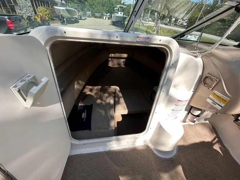 Slide: The Image of 2005 Chaparral 215 SSi boat cabin interior with open door, showing seating and carpeted floor. - 22
