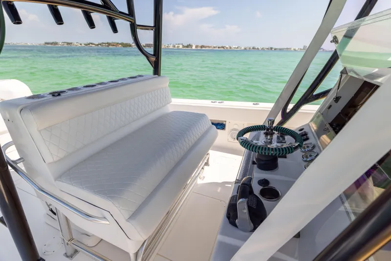 Slide: The Image of 2008 SeaVee 390 B boat interior with white seating and steering wheel, overlooking turquoise water. - 38