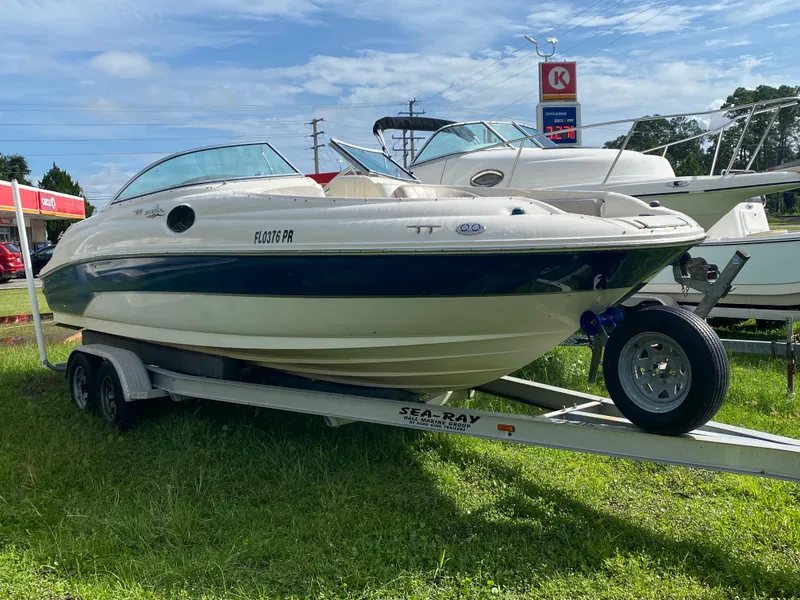 Slide: The Image of 2004 Sea Ray 240 Sundeck boat on trailer, parked on grass under a clear sky. - 1