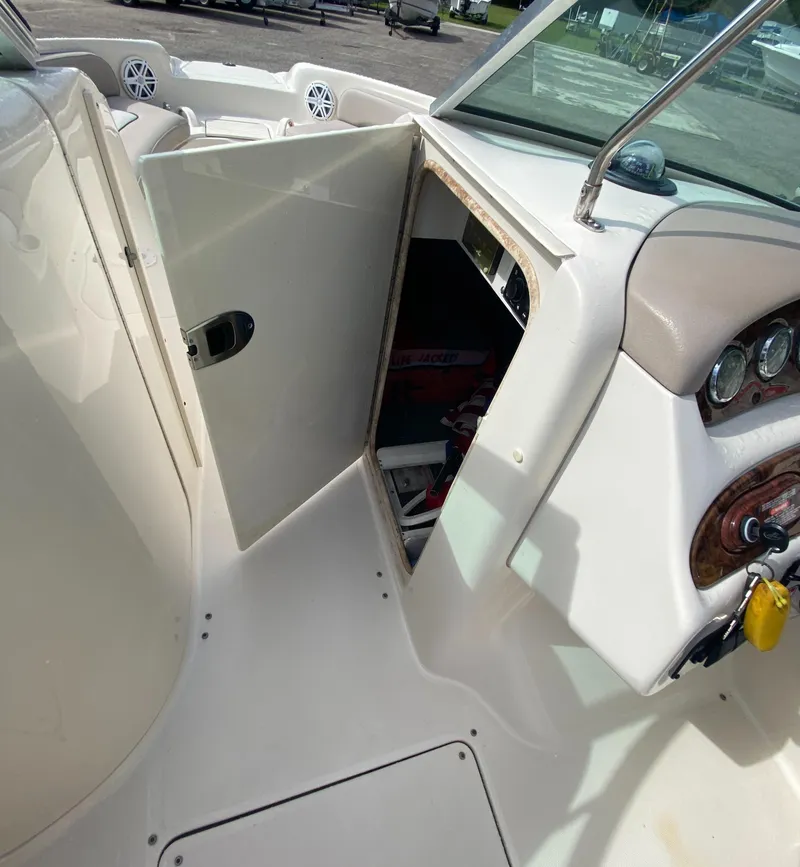 Slide: The Image of 2004 Sea Ray 240 Sundeck interior with open storage compartment and dashboard view. - 15