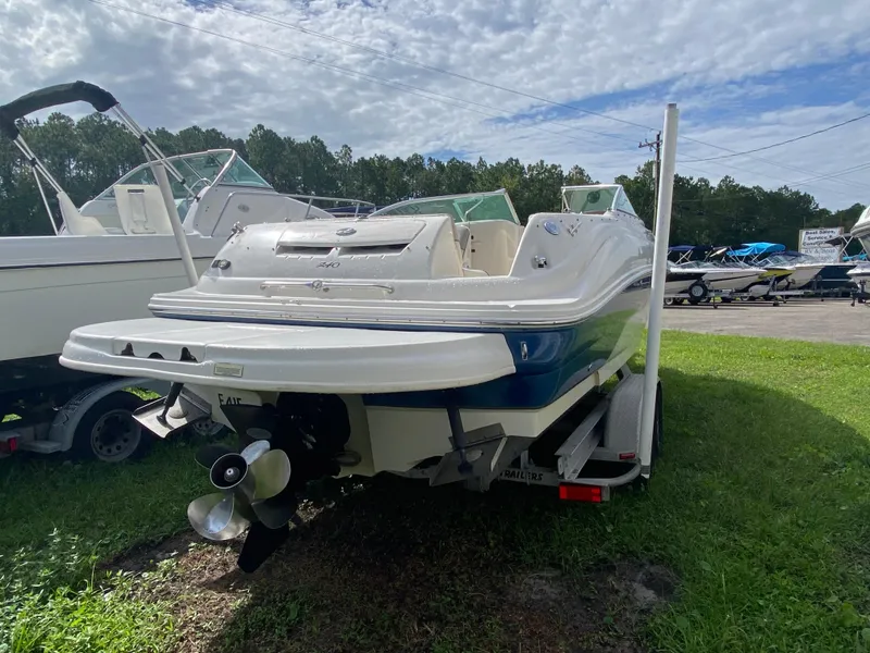 Slide: The Image of 2004 Sea Ray 240 Sundeck boat on trailer, parked on grass under cloudy sky. - 3