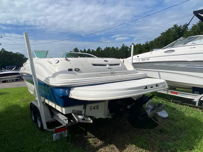 Slide: The Image of 2004 Sea Ray 240 Sundeck boat on trailer, parked on grass under a cloudy sky. - 4