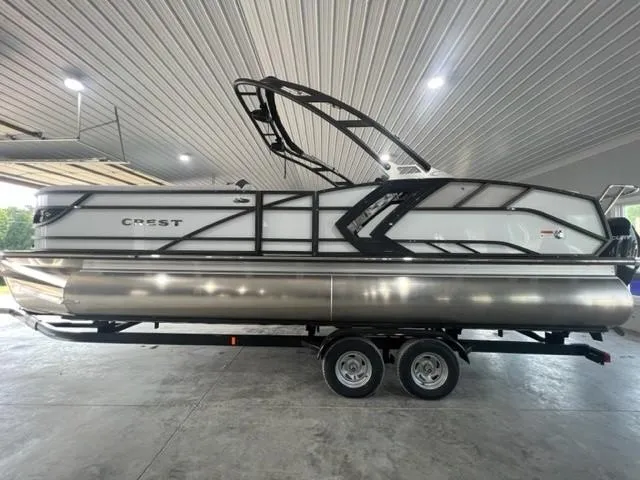 The Image of 2023 Crest Caribbean RS 250 SLC pontoon boat on trailer in a covered area. - 1