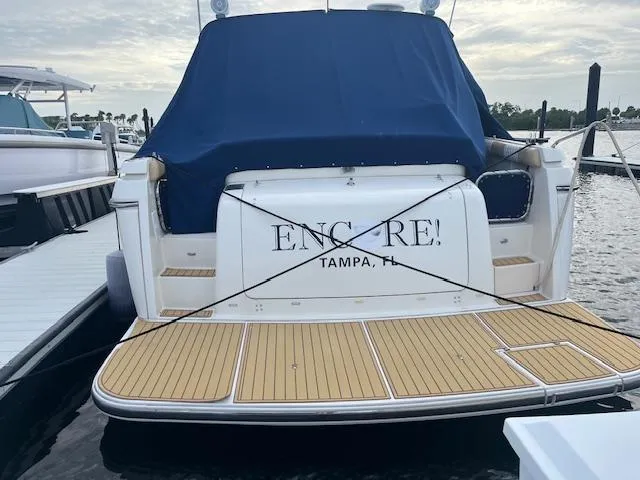Slide: The Image of 1996 Tiara Yachts 40 Express docked, rear view with blue cover, wooden deck, "Encore!" text. - 4