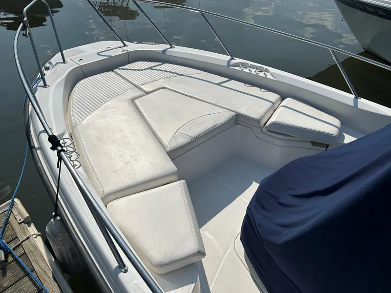 Slide: The Image of 2013 Boston Whaler 230 Dauntless boat with cushioned seating area, docked on calm water. - 15