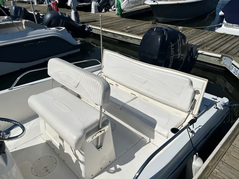 Slide: The Image of 2013 Boston Whaler 230 Dauntless boat with white seating and outboard motor at dock. - 5