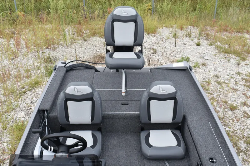 Slide: The Image of 2025 Lowe 16 Skorpion boat interior with three gray seats on gravel. - 8