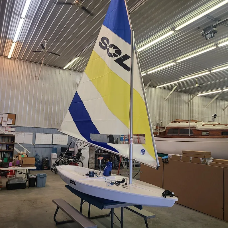 Slide: The Image of 2024 SERO Innovation SOL sailboat with colorful sail in a workshop setting. - 11