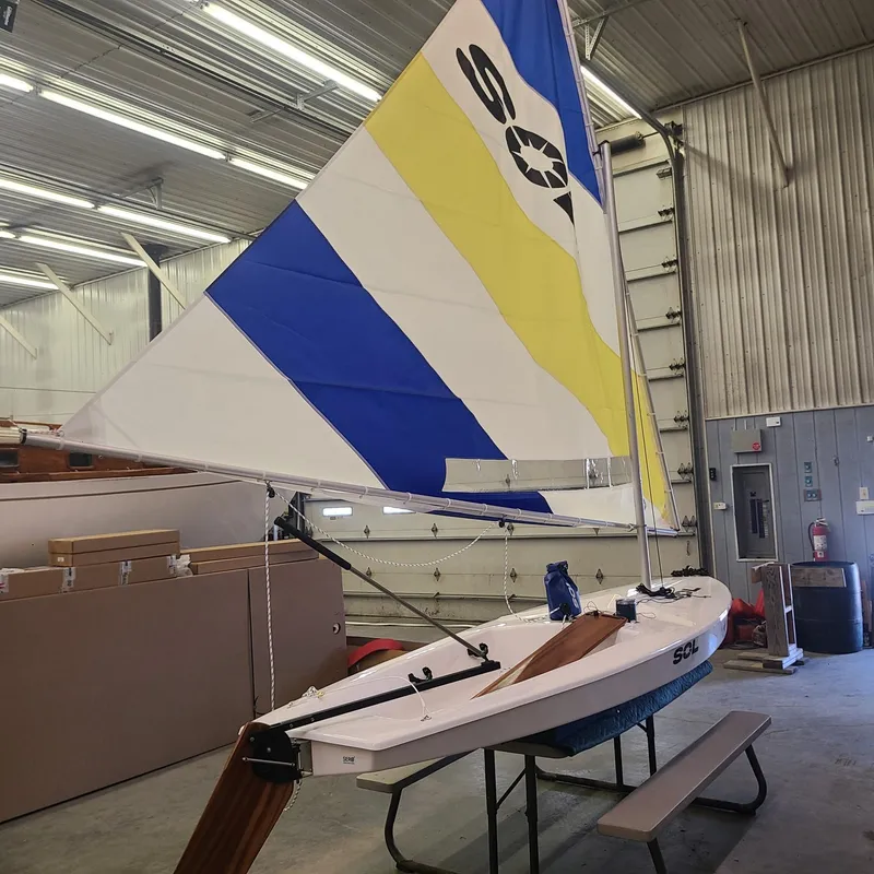 Slide: The Image of 2024 SERO Innovation SOL sailboat with colorful sail in indoor storage. - 9