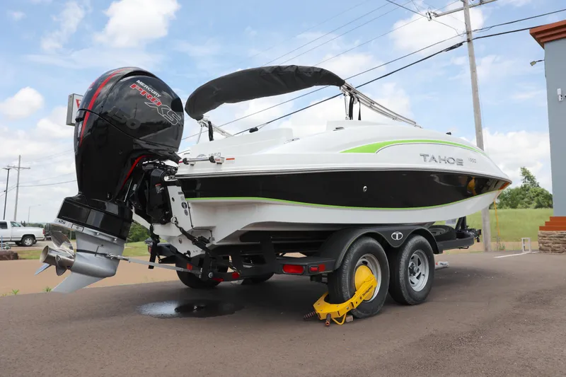 Slide: The Image of 2022 Tahoe 1950 boat on trailer with outboard motor, parked on road. - 2