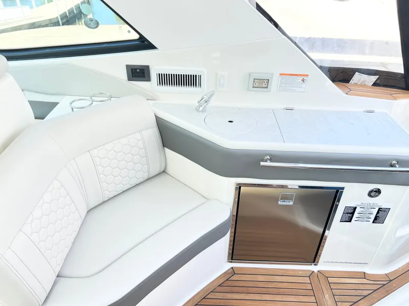 Slide: The Image of 2025 Sea Ray Sundancer 320 interior with white seating and modern kitchenette. - 5