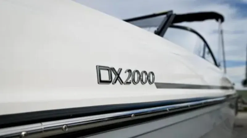 Slide: The Image of 2024 Bayliner DX2000 boat, close-up of model name on sleek white hull. - 2