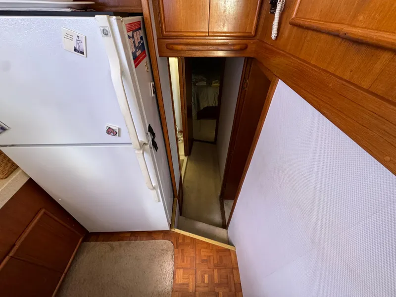 Slide: The Image of 1990 Post 44 Sport Fisherman interior with wood cabinetry and white refrigerator. - 18