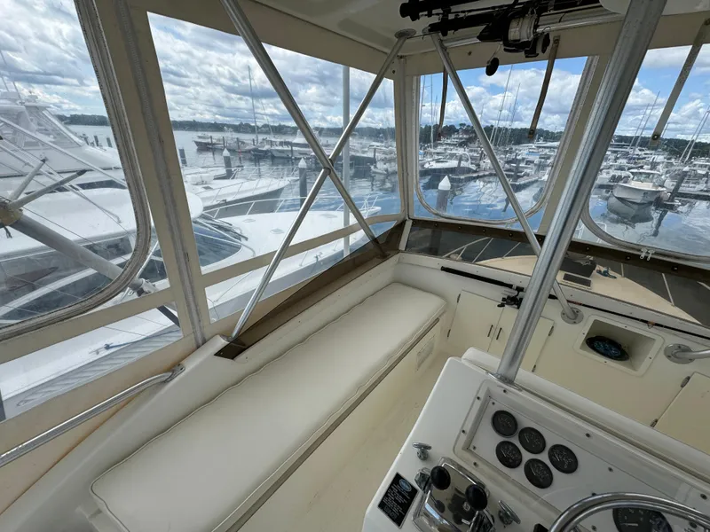 Slide: The Image of 1990 Post 44 Sport Fisherman interior with marina view, featuring helm and seating area. - 37