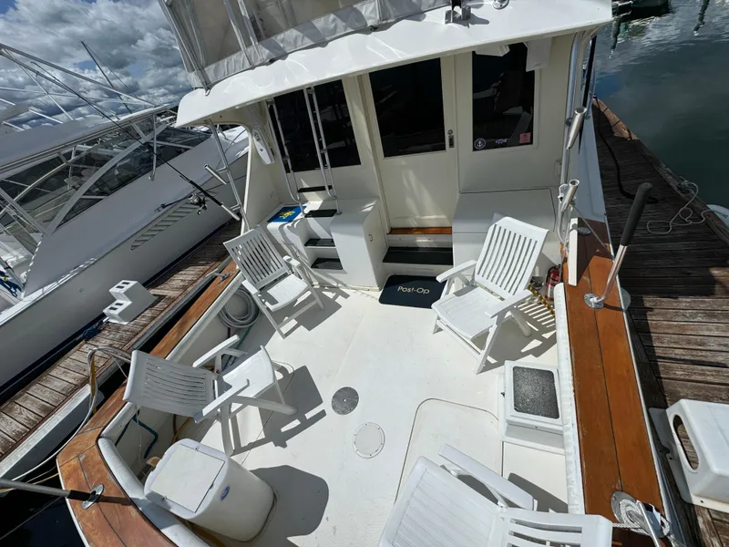 Slide: The Image of 1990 Post 44 Sport Fisherman boat deck with white chairs and wooden accents. - 6