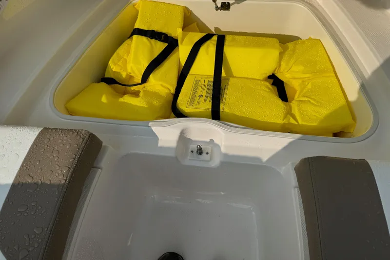 Slide: The Image of Yellow life jackets in storage compartment of 2022 Robalo R207 Dual Console boat. - 17