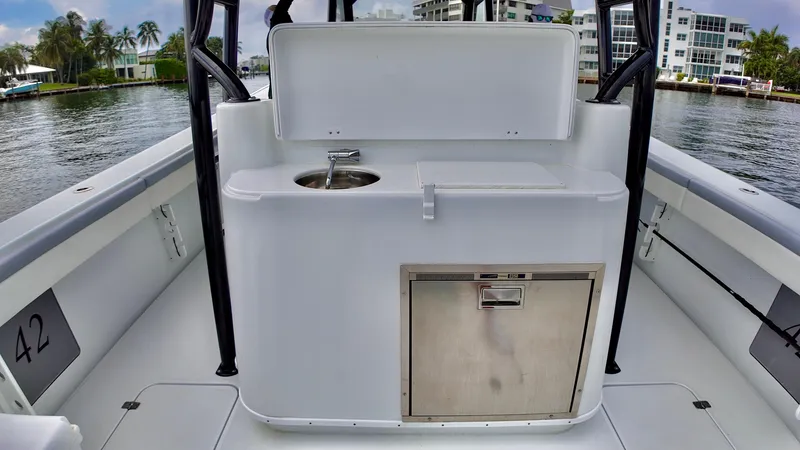 Slide: The Image of 2022 Yellowfin 42 Offshore boat interior with sink and storage, docked by waterfront homes. - 13