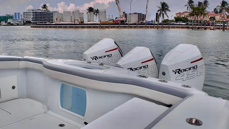 Slide: The Image of 2022 Yellowfin 42 Offshore boat with triple Racing 450 engines docked by palm trees. - 2