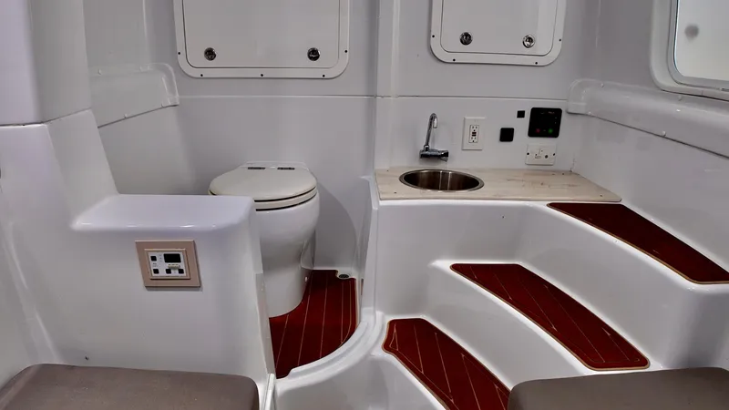 Slide: The Image of 2022 Yellowfin 42 Offshore boat interior with toilet, sink, and wooden steps. - 22