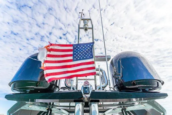 Slide: The Image of Monte Carlo Yachts MCY 70, 2018 model, with American flag against a cloudy sky. - 35