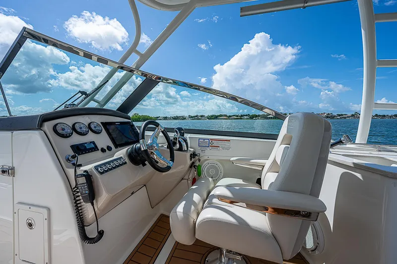 Slide: The Image of 2018 Boston Whaler 270 Vantage boat cockpit with steering wheel and controls, under blue sky. - 37