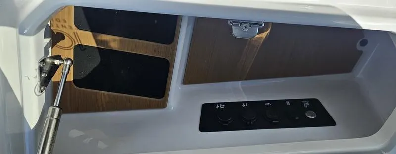 Slide: The Image of 2025 Nautique Super Air Nautique G23 interior control panel and storage compartment. - 22