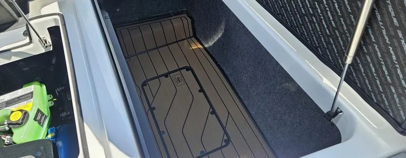 Slide: The Image of 2025 Nautique Super Air Nautique G23 storage compartment with open hatch and visible battery. - 39