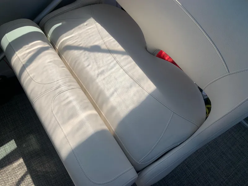 Slide: The Image of 2018 Crownline 264 CR boat seat with beige upholstery and sunlight shadows. - 11