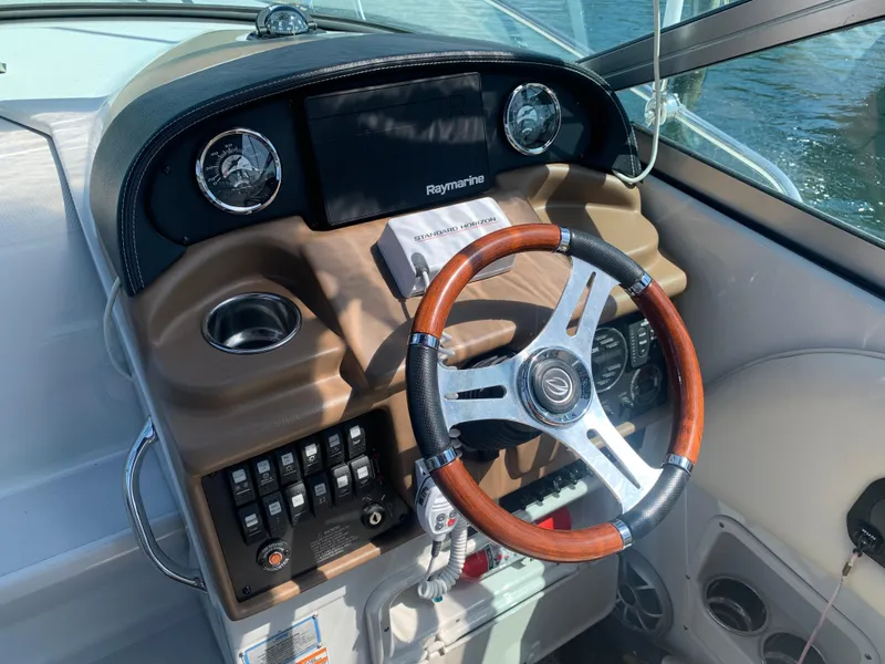 Slide: The Image of 2018 Crownline 264 CR boat dashboard with wood-accented steering wheel and navigation controls. - 13